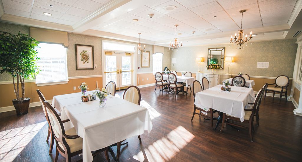 An elegantly designed dining area with neatly set tables and chairs, featuring warm lighting and tasteful decor.