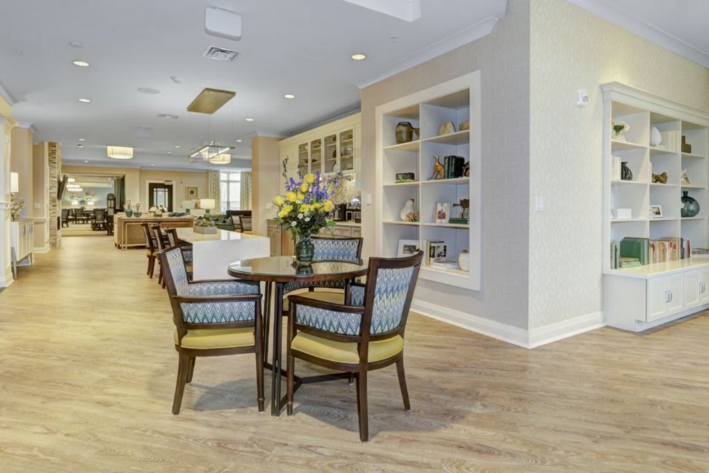 A modern interior space featuring a round table with chairs, decorated with a vase of flowers and surrounded by built-in shelves.