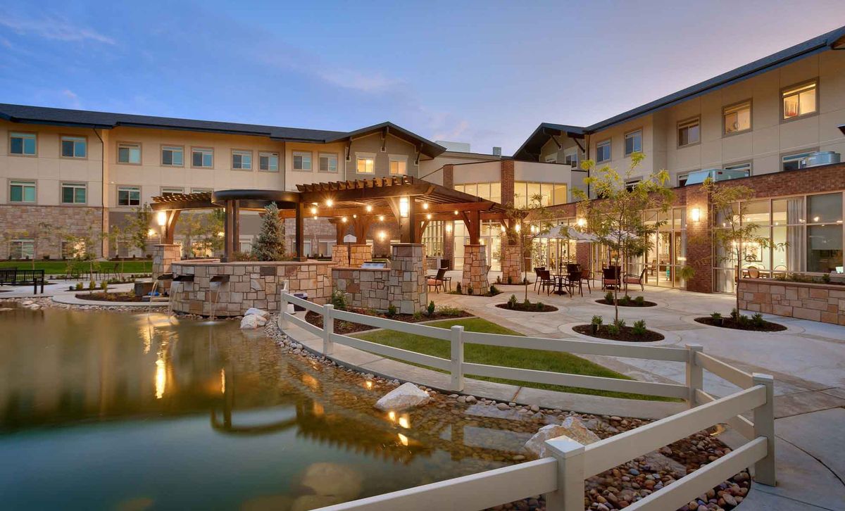 A beautifully lit building with a serene pond and landscaped outdoor area during the evening.