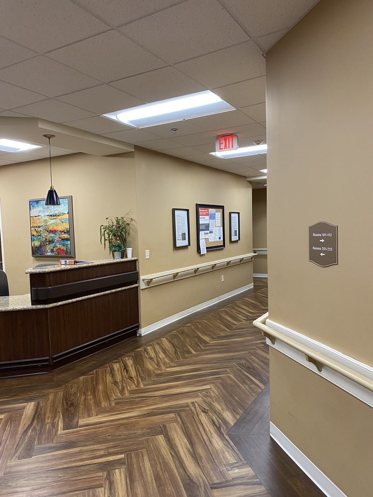 A view of a reception area with a desk and hallway in an office setting featuring artwork and wooden flooring.