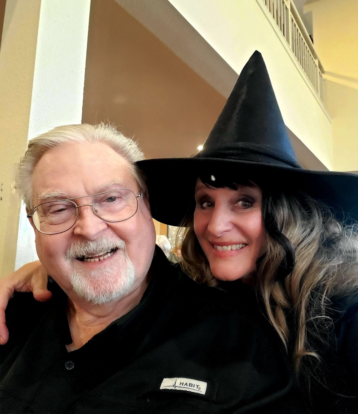A joyful moment with a smiling pair, one wearing a witch hat.
