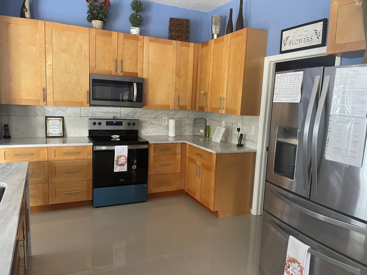 A modern kitchen with wooden cabinets, stainless steel appliances, and decorative plants.