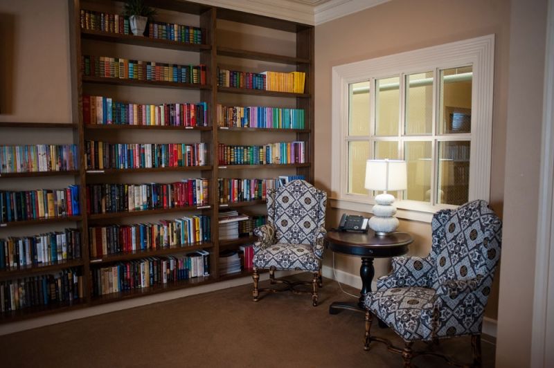 A cozy reading corner with bookshelves, two patterned chairs, and a lamp.