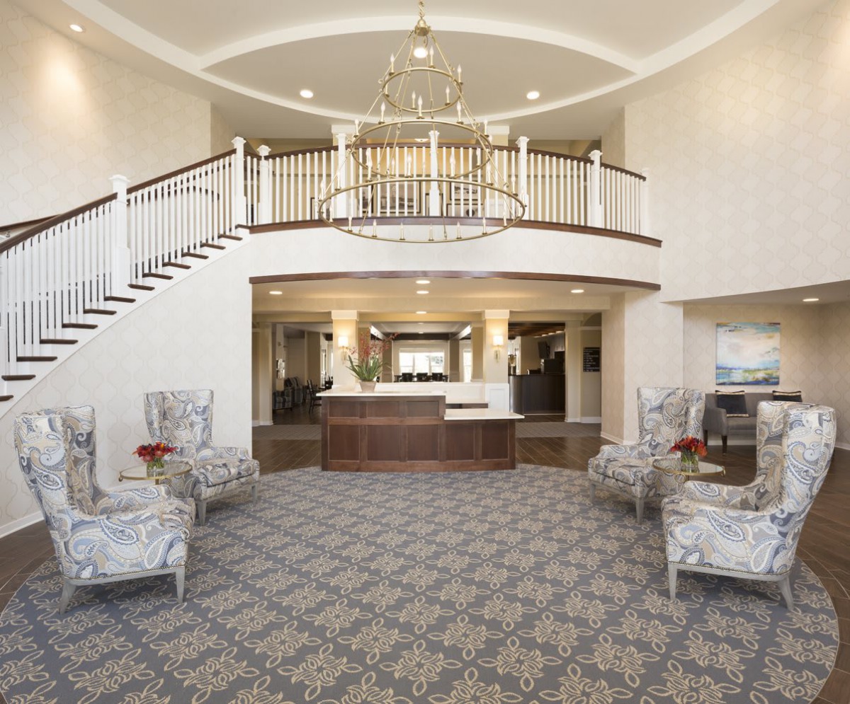 Elegant hotel lobby with a grand staircase and chandelier.