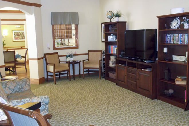 A cozy living room with a television, shelving unit, and seating area.