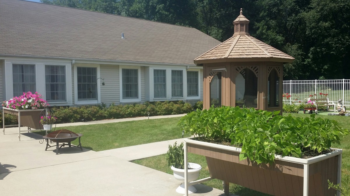A sunny outdoor garden area with a small gazebo and adjacent building.