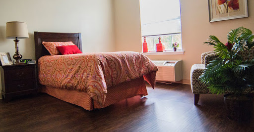 A cozy bedroom featuring a neatly made bed, wooden flooring, and vibrant decorative elements.
