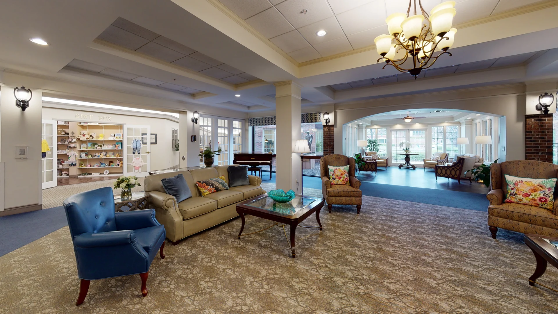 A spacious and elegantly designed lobby area featuring comfortable seating and a chandelier.