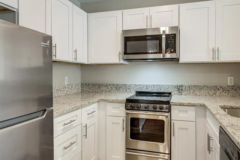 A modern kitchen featuring stainless steel appliances and white cabinetry.