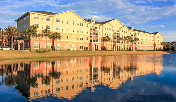 A picturesque view of apartments with their reflection in a calm lake during sunset.