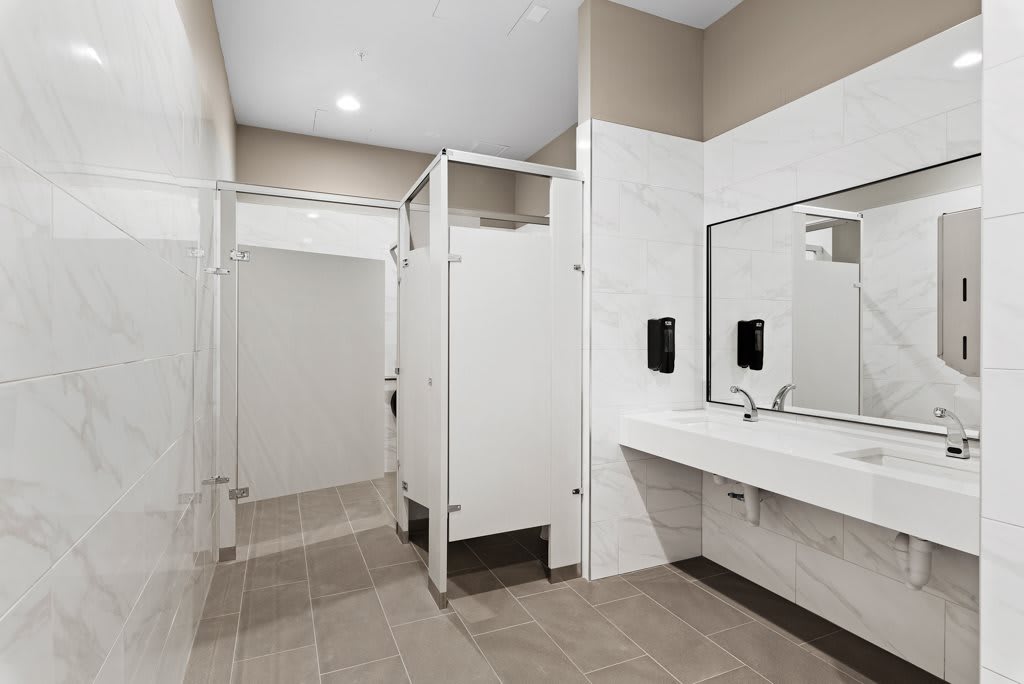A clean and modern public restroom with stalls, sinks, and mirrors.
