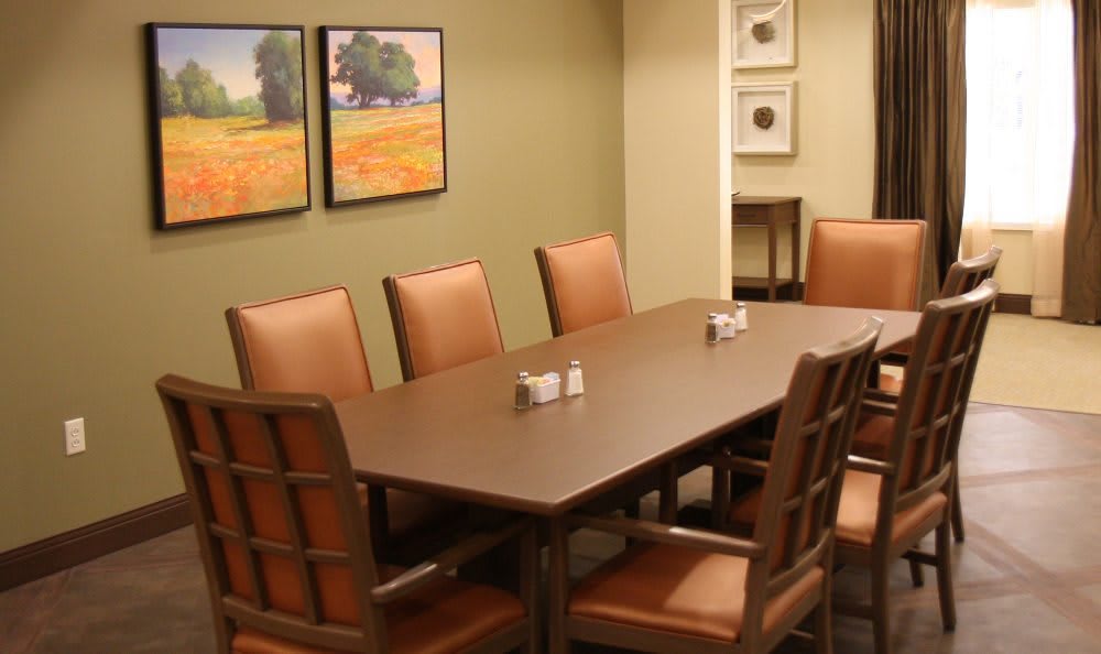 A neat conference room with a rectangular table surrounded by several chairs, adorned with artwork on the walls.