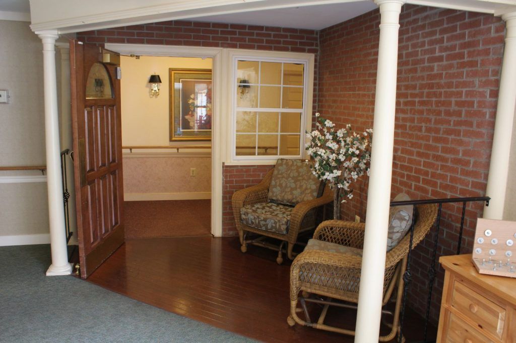 A cozy lobby area with wicker chairs against a brick wall and wooden flooring.