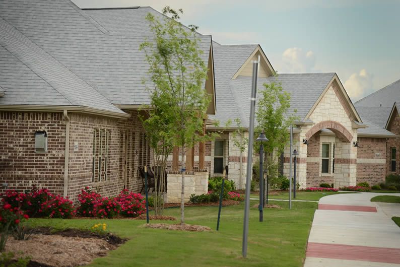 A row of suburban houses with well-maintained lawns and landscaping.