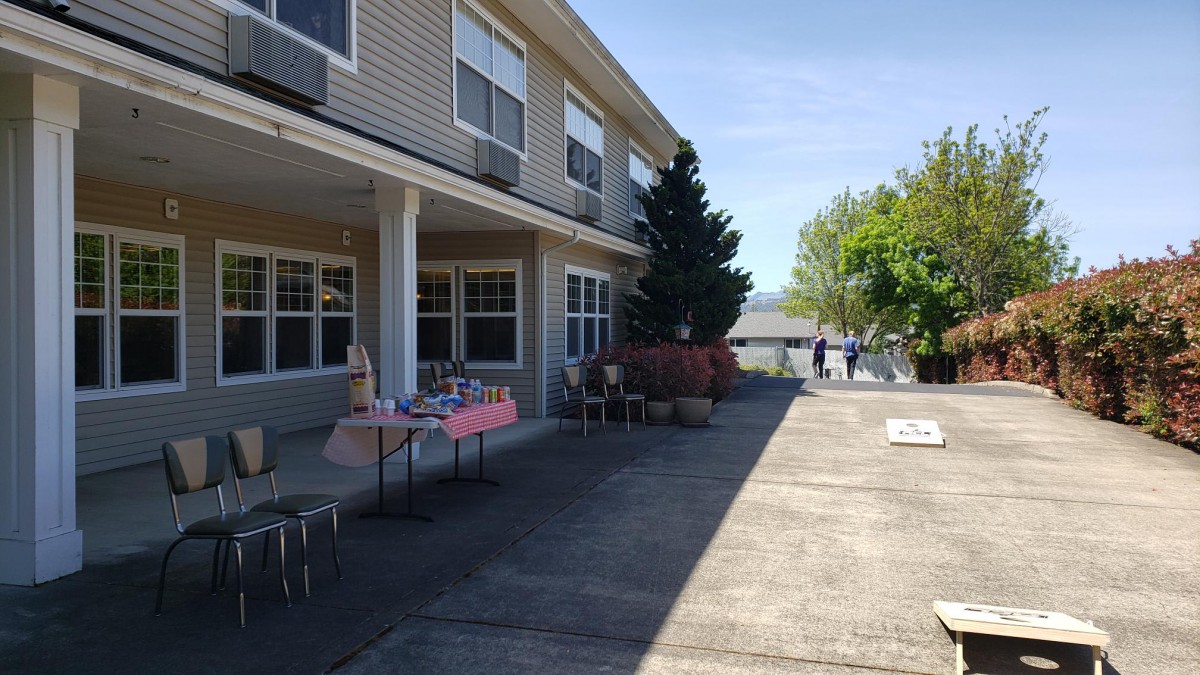 Outdoor view of a building with tables set up on the sidewalk and trees nearby.