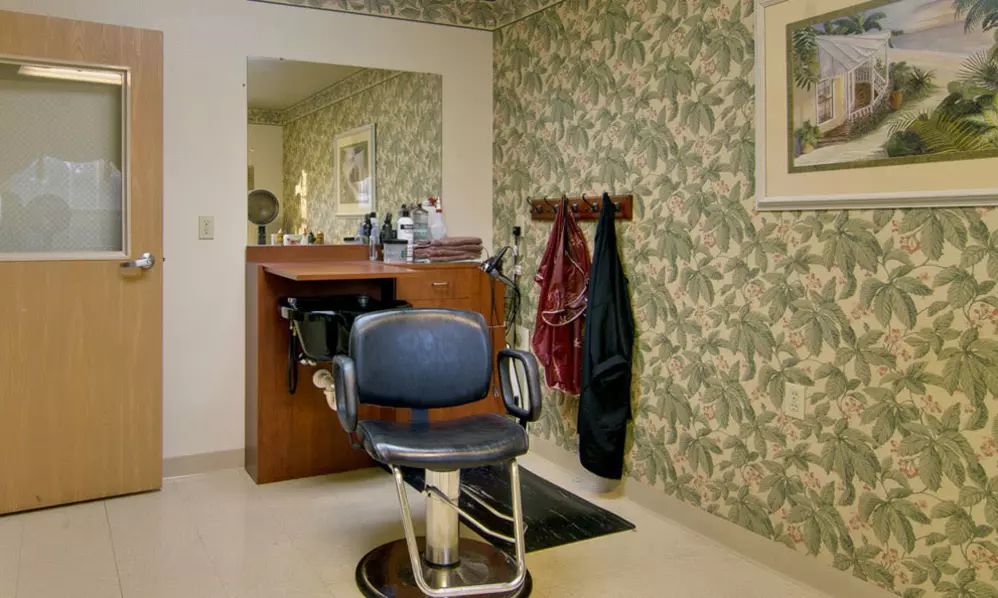 A cozy salon with a single barber chair in front of a mirror, featuring patterned wallpaper.