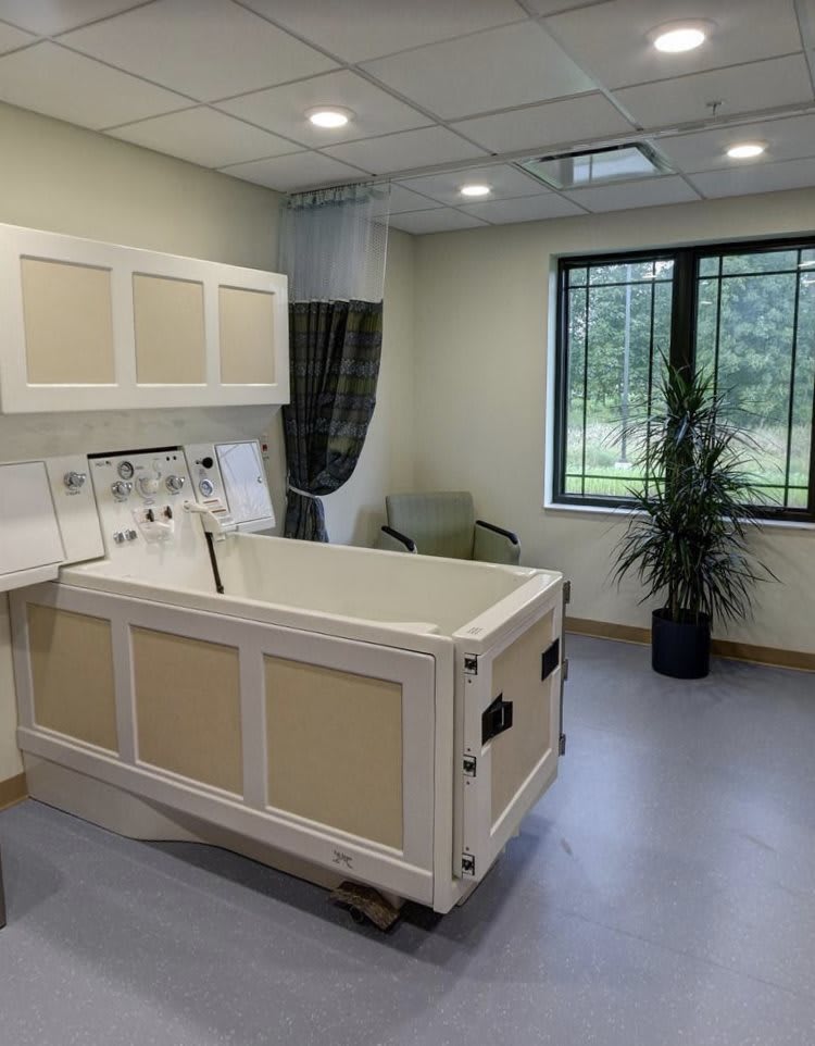 A hospital room with medical equipment, featuring a patient bed and modern interior design.