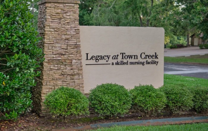 Sign for Legacy at Town Creek, a skilled nursing facility, surrounded by greenery.