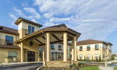 A residential building with a grand entrance supported by columns under a partly cloudy sky.