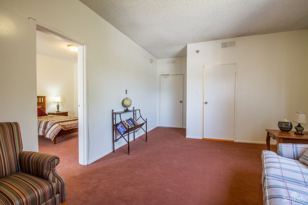 A cozy living room with carpeted flooring and simple furnishings.