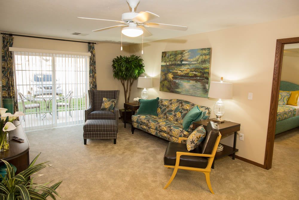 A cozy living room with a sofa, armchair, and accent chair, featuring warm lighting and decorative artwork.
