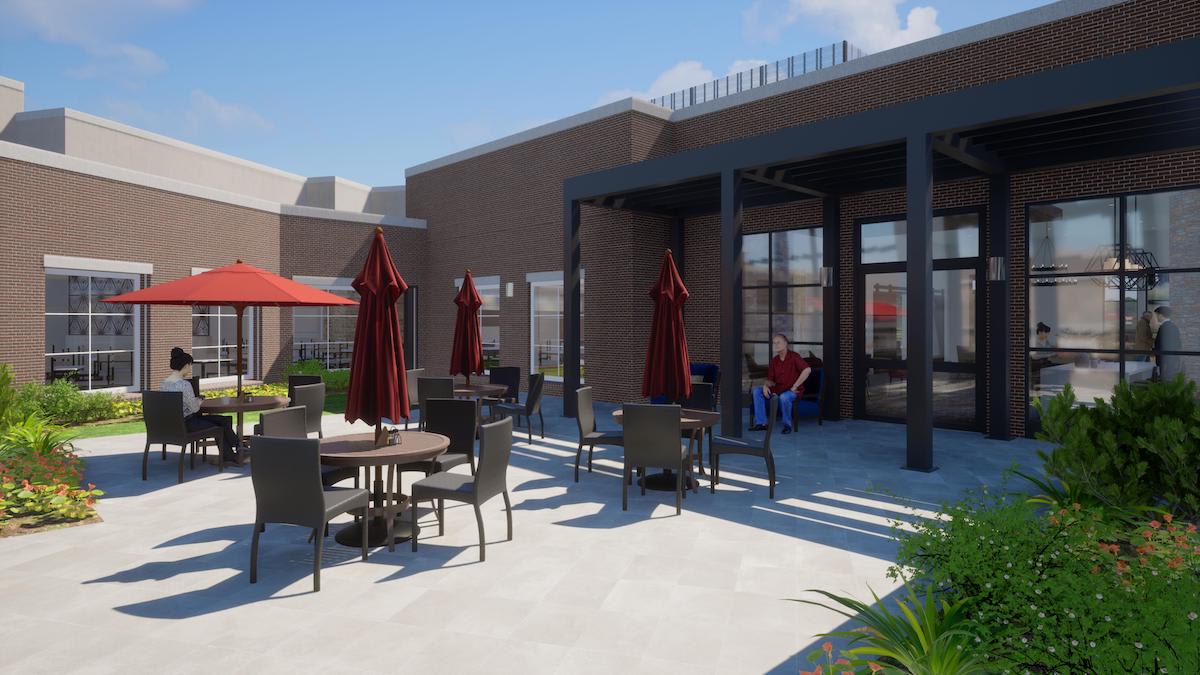 A modern outdoor patio area with tables, chairs, and red umbrellas next to a building.