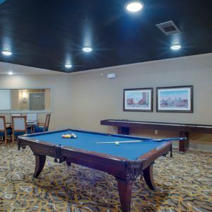 A well-lit game room featuring a billiards table and seating area.