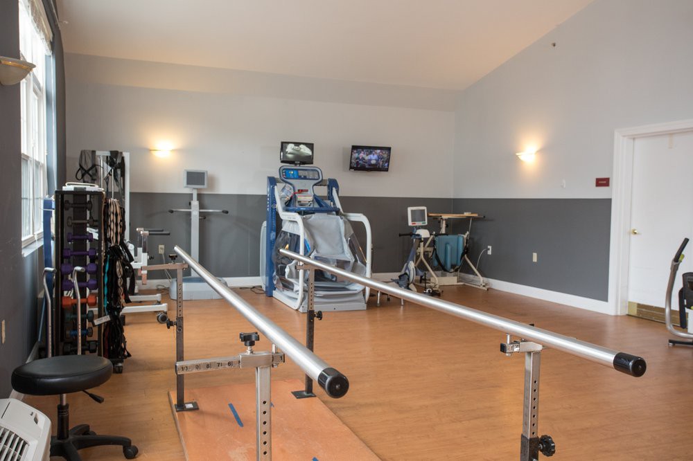 A physical therapy room equipped with exercise machines and parallel bars for rehabilitation.