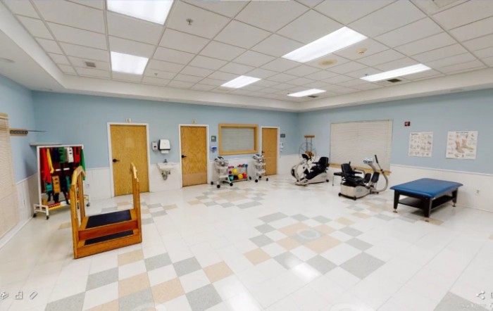 A spacious rehabilitation room equipped with various exercise machines and equipment for physical therapy.