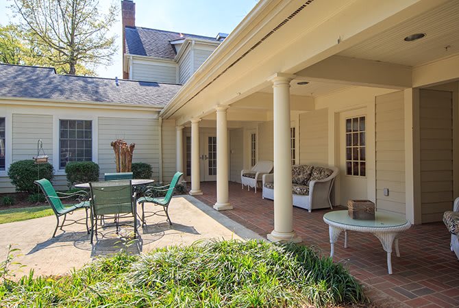 A cozy patio area with outdoor seating and a table, featuring classic columns.