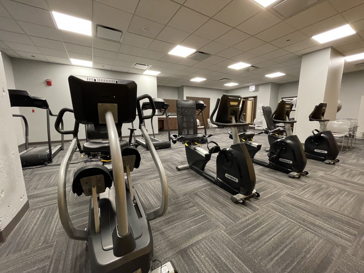 A modern gym with various exercise machines, including stationary bikes and ellipticals.