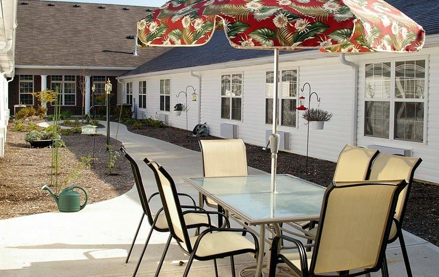 An outdoor patio area with a table, chairs, and an umbrella, adjacent to a residential building.