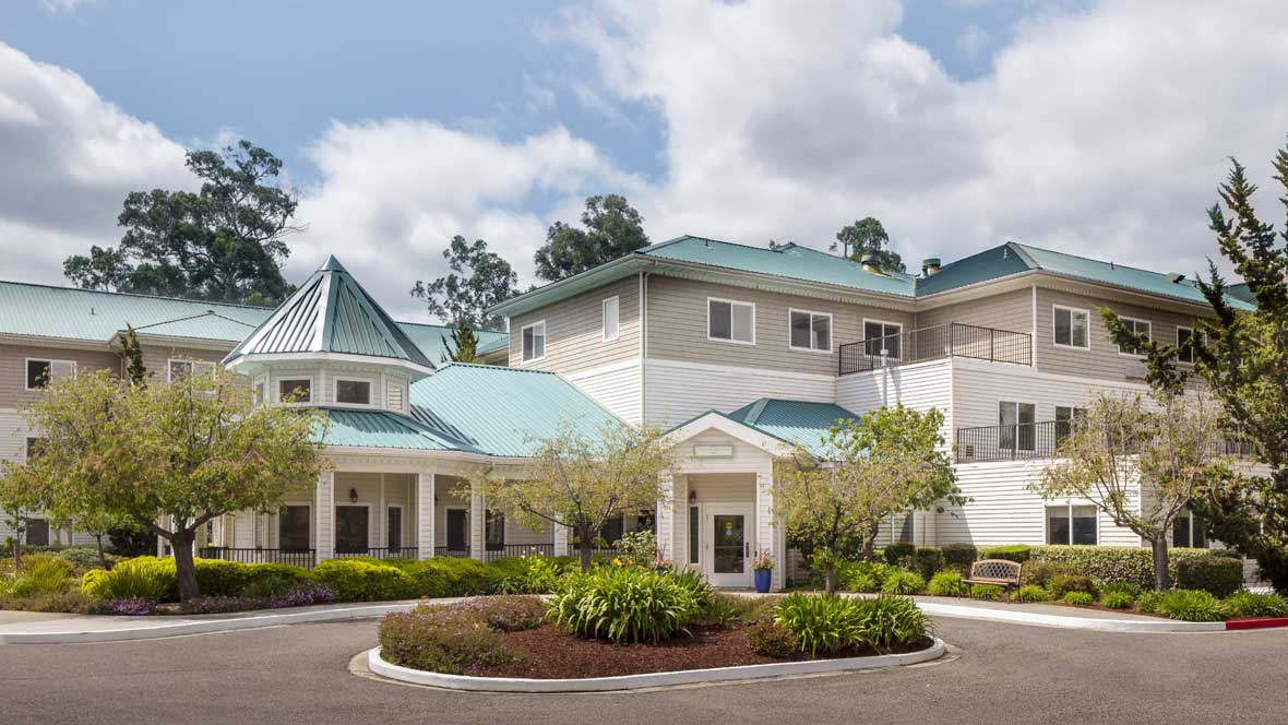 A modern residential building with a landscaped entrance and clear sky.