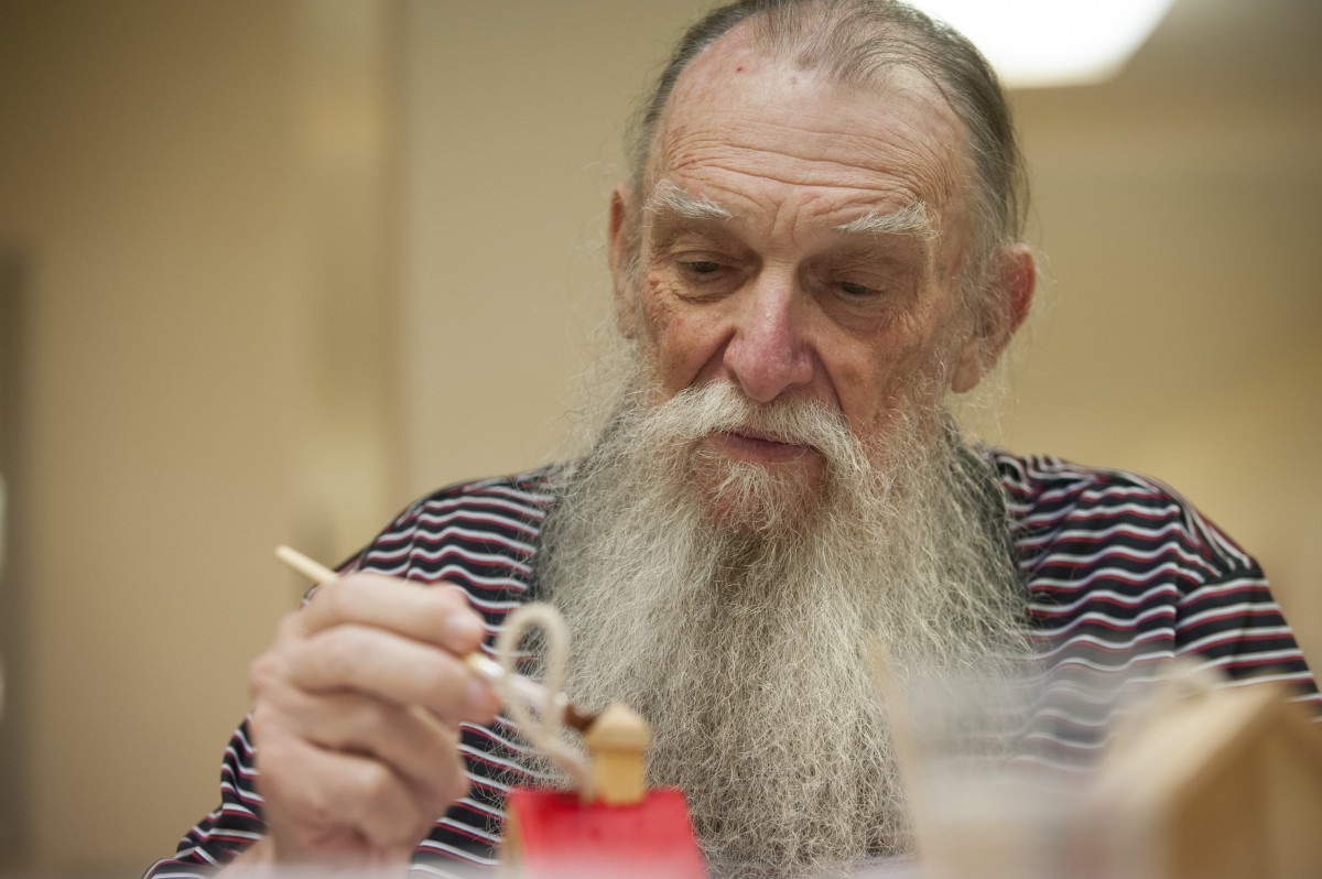 An elderly man with a long beard using chopsticks to eat.