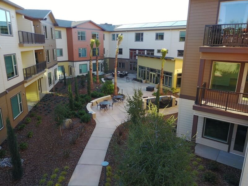 A view of a well-landscaped apartment complex courtyard with pathways and outdoor seating areas.