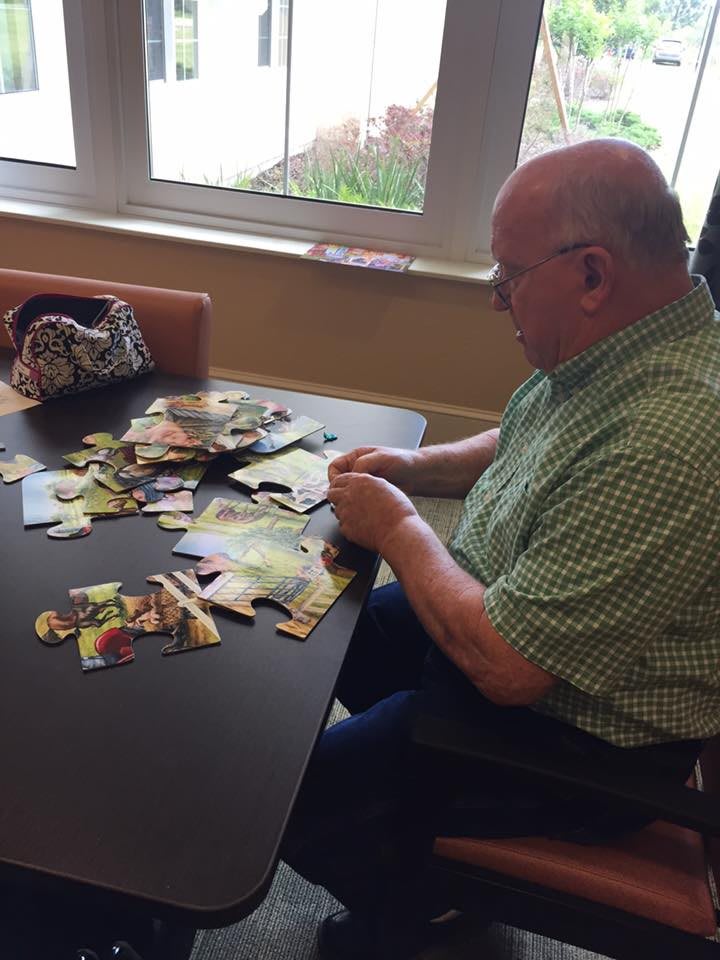 A man working on a puzzle at a table indoors.