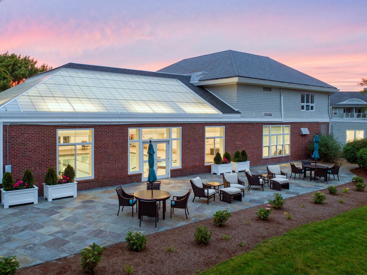 A modern building with outdoor patio seating and landscaped surroundings during sunset.