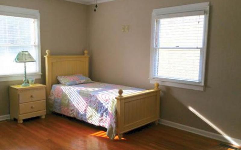 A minimalist bedroom with a single bed and sunlight streaming through the window.
