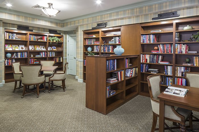 A cozy library with bookshelves and a reading area featuring tables and chairs.