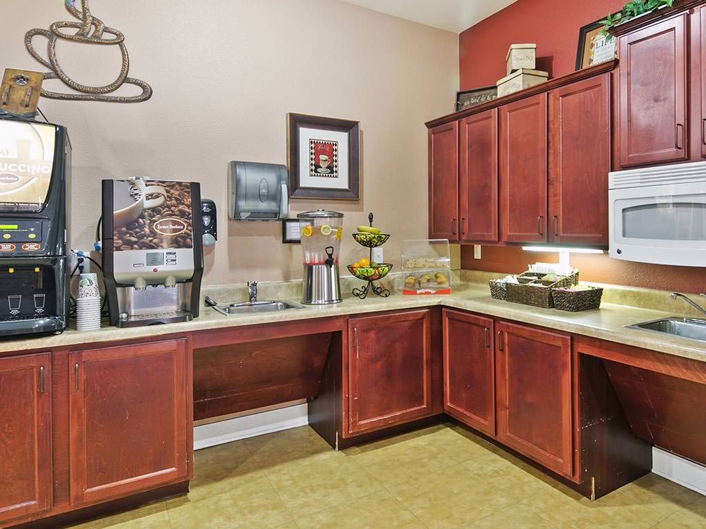 A kitchen area featuring a coffee machine, wooden cabinets, and decorative items.
