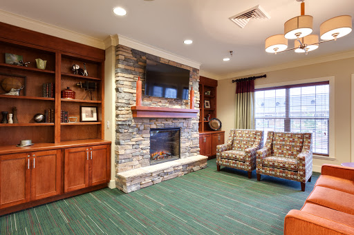 A cozy living room featuring a stone fireplace, comfortable seating, and modern decor.