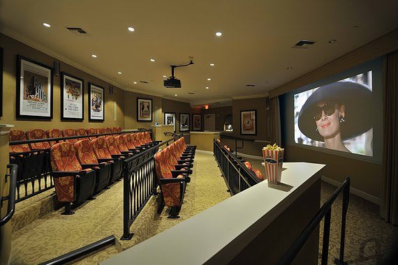 A luxurious home theater with comfortable seating and movie posters on the walls.