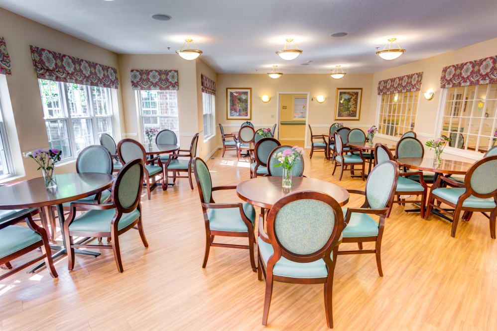 A cozy dining area with elegant chairs and tables, well-lit by overhead lights and natural light from the windows.