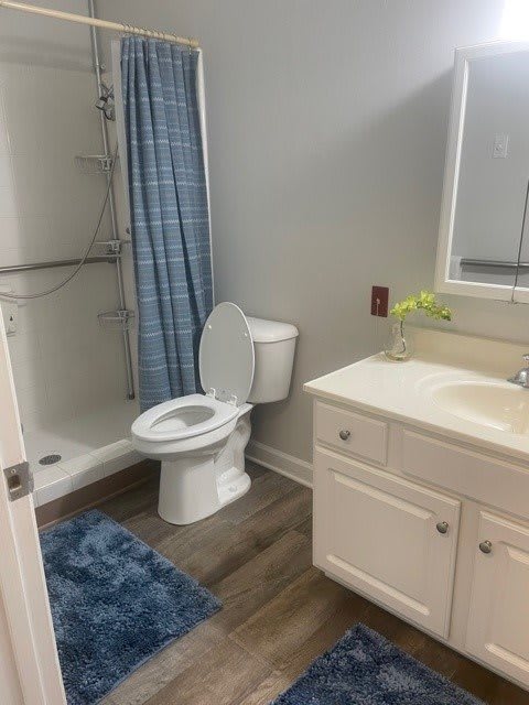 A modern and clean bathroom featuring a toilet, sink, and shower with a blue curtain.
