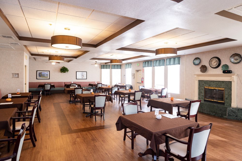 An empty dining room with neatly arranged tables and chairs, featuring wooden floors and modern light fixtures.