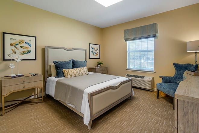 A well-designed bedroom featuring a comfortable bed with decorative pillows, neutral walls, and elegant furnishings.