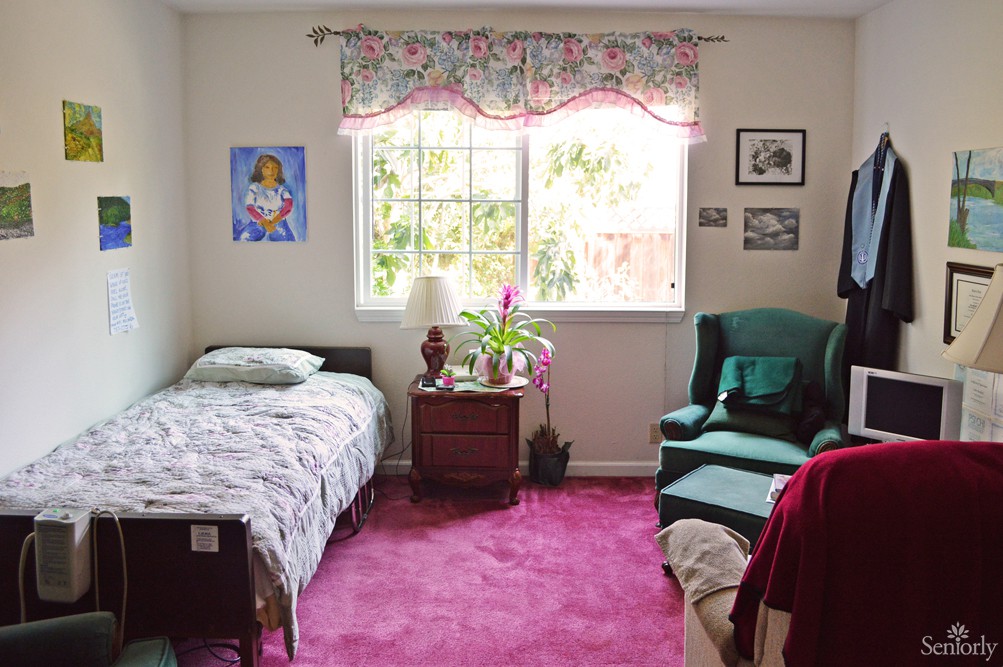 A cozy bedroom with a single bed, an armchair, and a window bringing in natural light.
