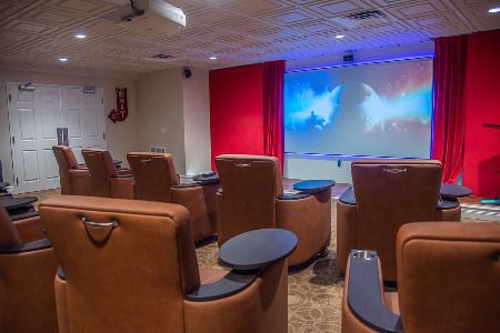 A modern home theater setup with comfortable recliner chairs and a large projector screen.