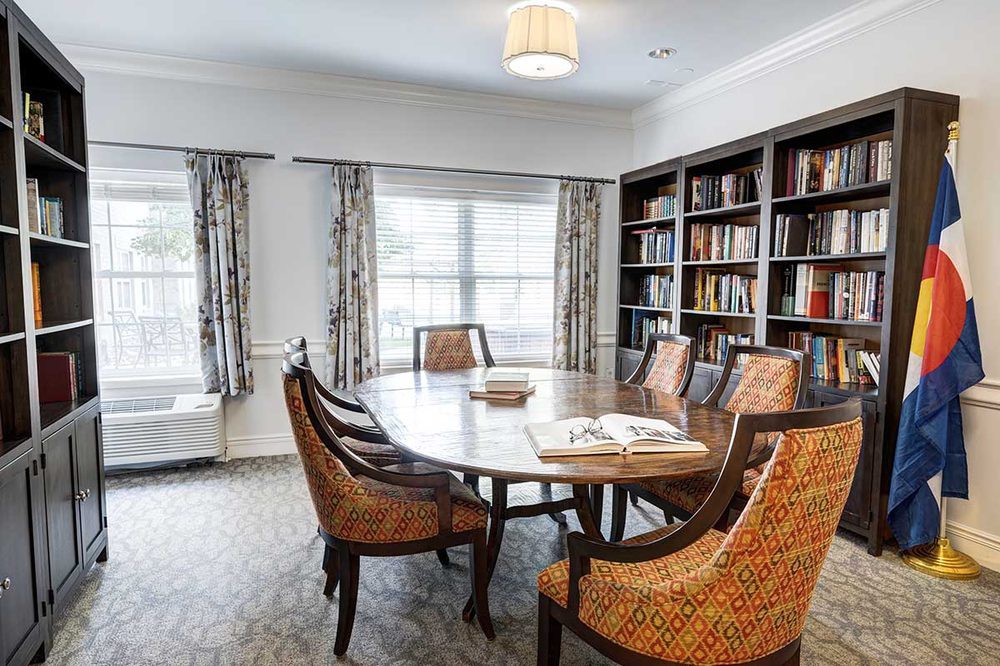 A cozy meeting room with a round table surrounded by chairs and bookshelves filled with books.