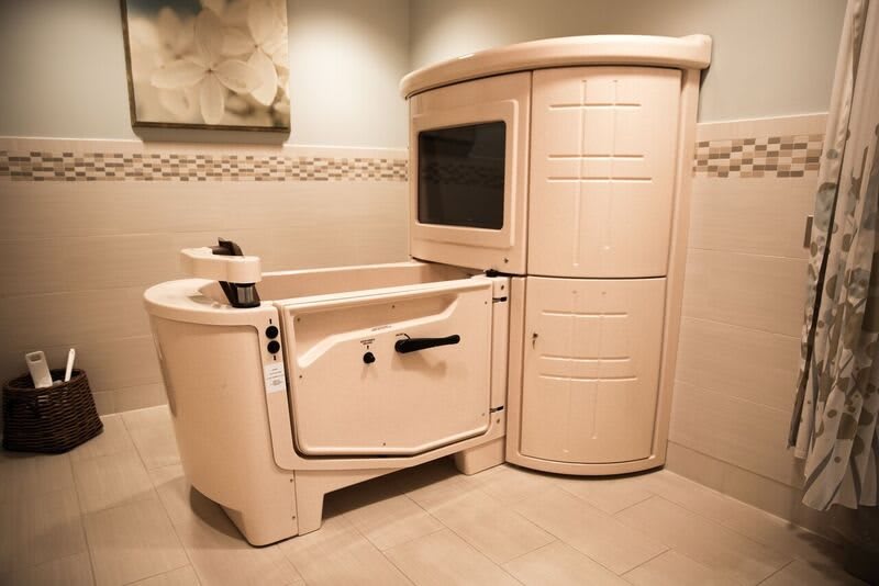 A beige walk-in bathtub designed for accessibility in a modern bathroom.